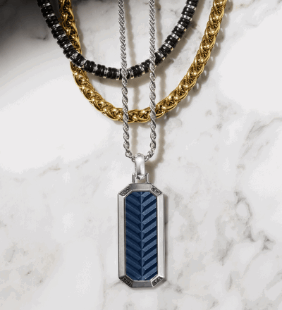 Layered men’s necklaces on marble background.
