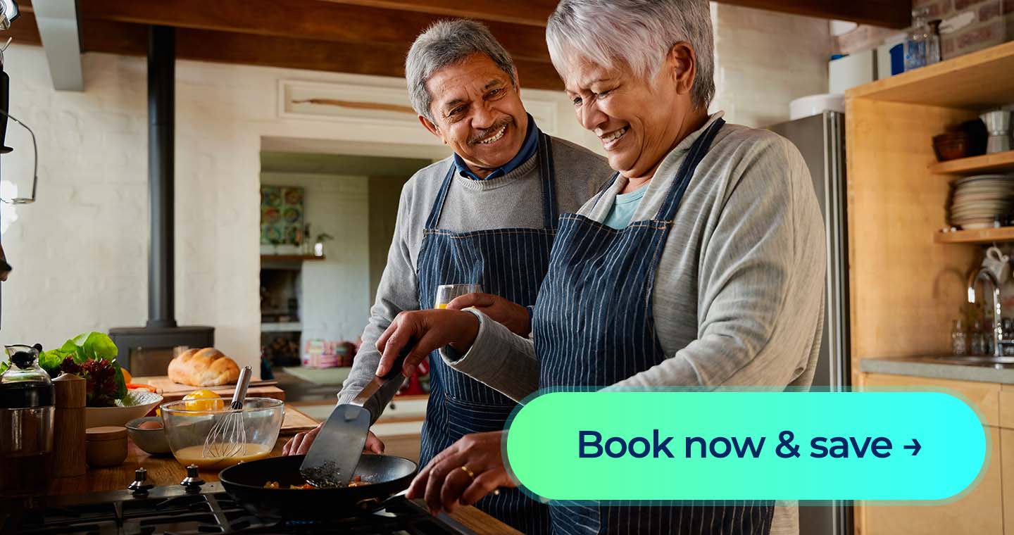 A man and woman cooking their dinner on a stove while laughing