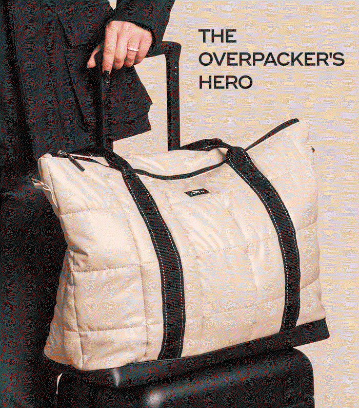 THE OVERPACKER'S HERO. Person holding a beige quilted travel bag on top of a black suitcase.