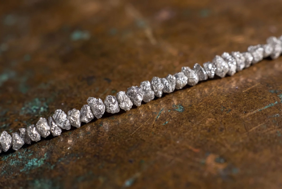 Raw silvery diamonds catching light across their natural surfaces