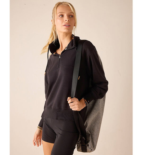 Image of a woman wearing a black French terry quarter zip sweatshirt