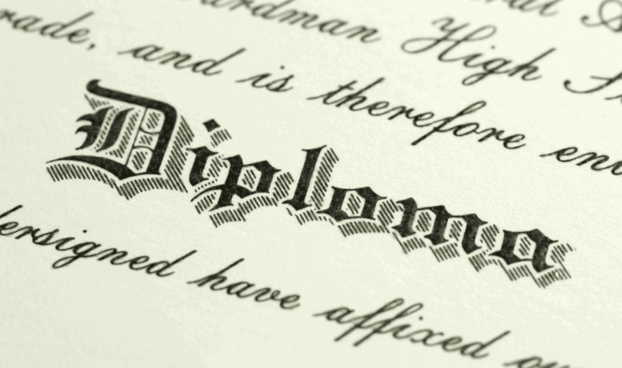 Close-up of a diploma document featuring the word "Diploma" in ornate, blackletter font with surrounding text in cursive script.
