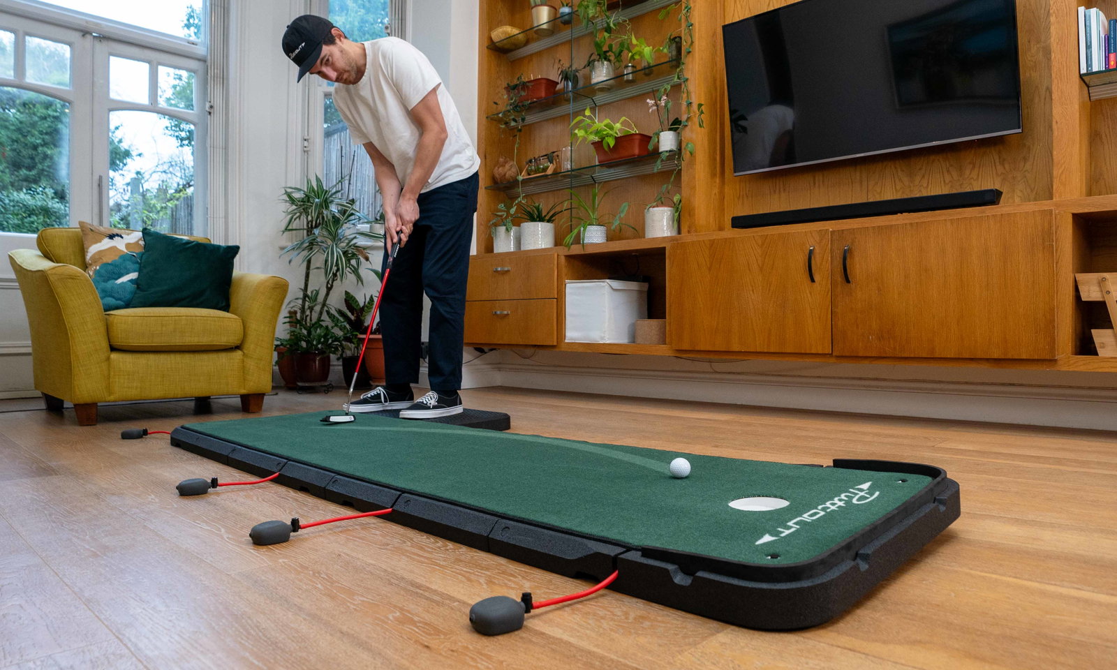 Man practicing Putting in his living room using putting mat