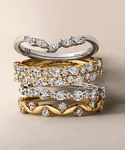 Stacked diamond wedding bands in yellow and white gold with round and marquise-cut diamonds.