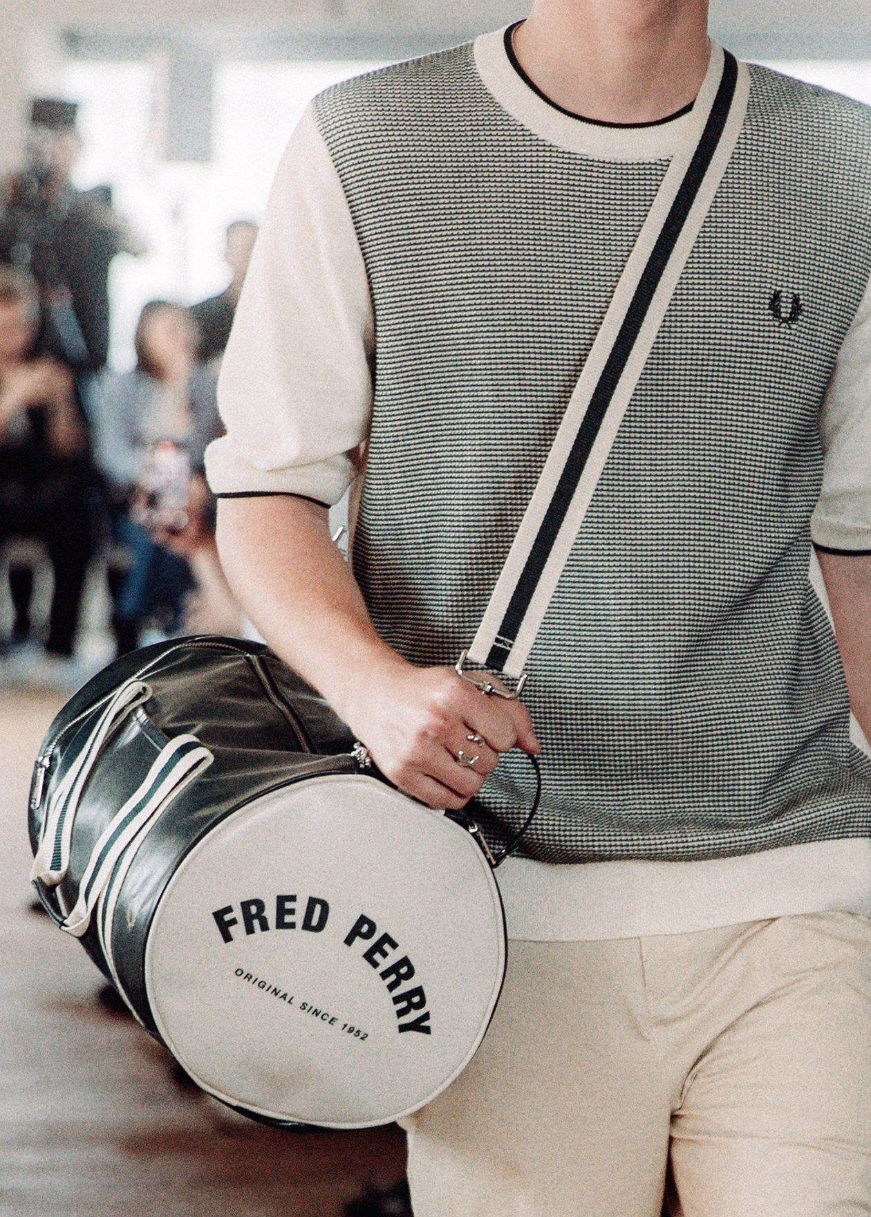 Male model carrying the Fred Perry Classic Barrel Bag in Grassroots / Ecru