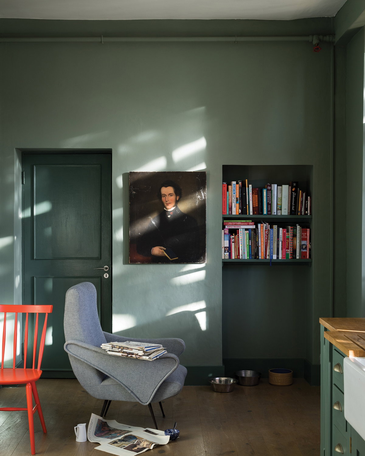 Reading corner painted in Green Smoke, featuring a purple armchair, artwork and houseplants.