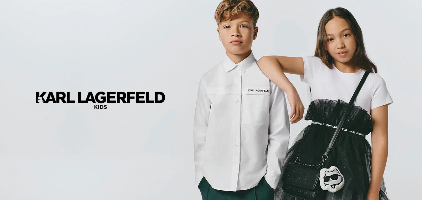 Jonge jongen en meisje staan naast elkaar; de jongen draagt een wit overhemd en donkere broek, het meisje draagt een wit topje en een zwarte gelaagde rok met een schoudertas.