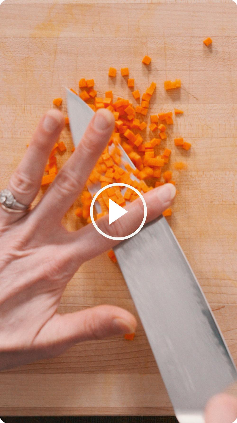 Hand dicing carrots on a cutting board — watch the video