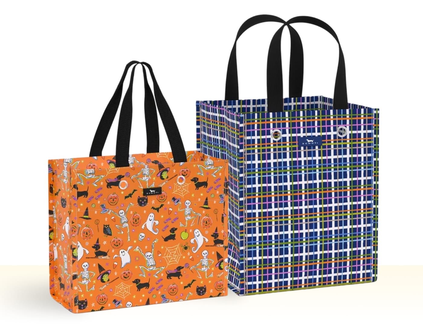 Two SCOUT reusable bags, one with a Halloween pattern and one with a blue plaid pattern.