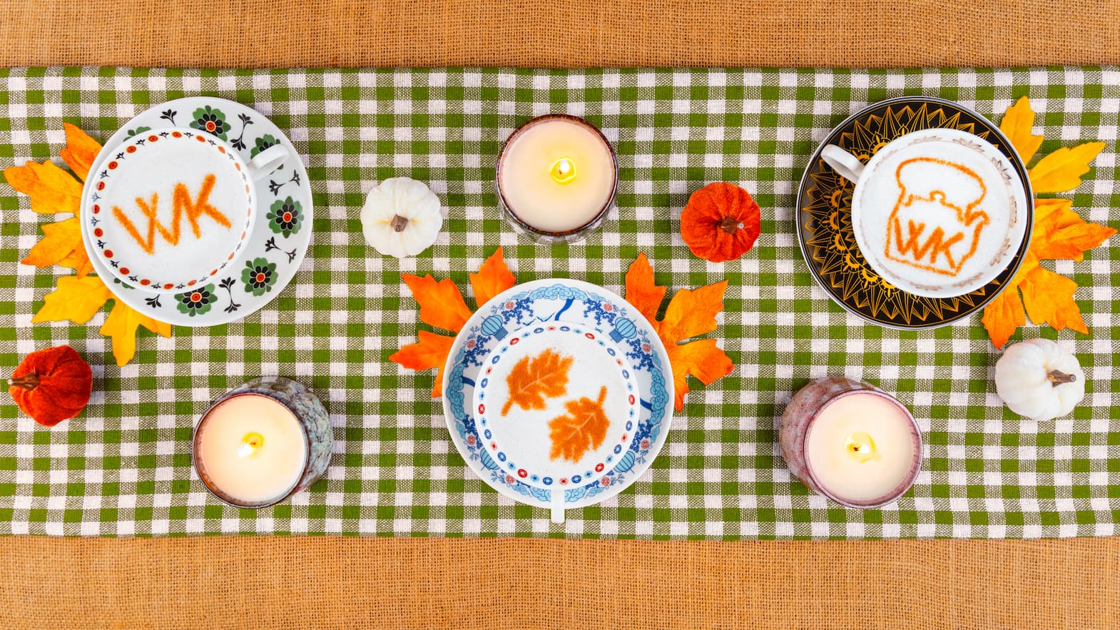 Hot tea lattes surrounded by candles, fall leaves, apples and pumpkins