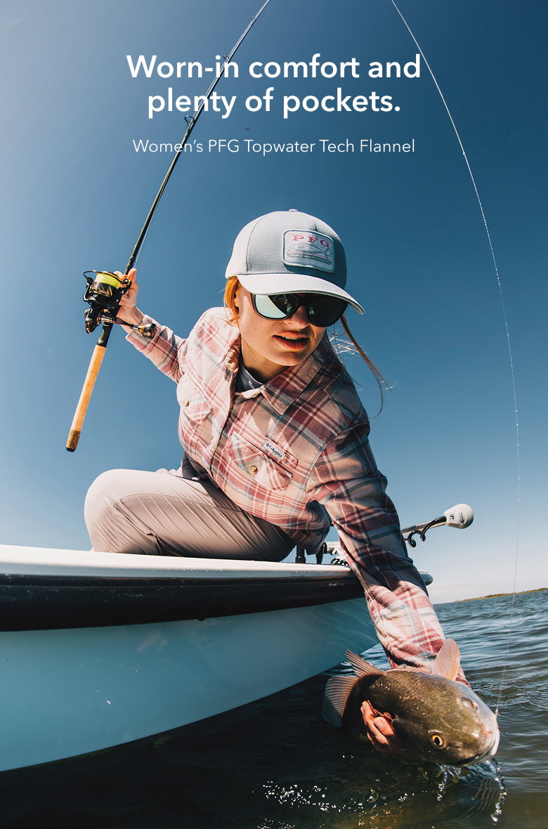 A woman sitting on a boat, holding a fishing rod with text: Worn-in comfort and plenty of pockets. Women's PFG Topwater Tech Flannel