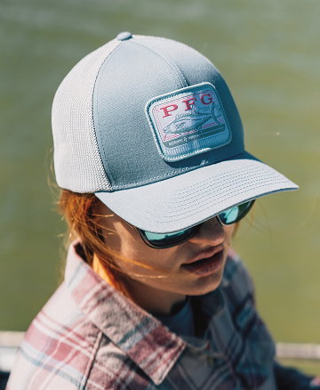 Close-up of a woman's light blue ball cap with a PFG patch on the front.