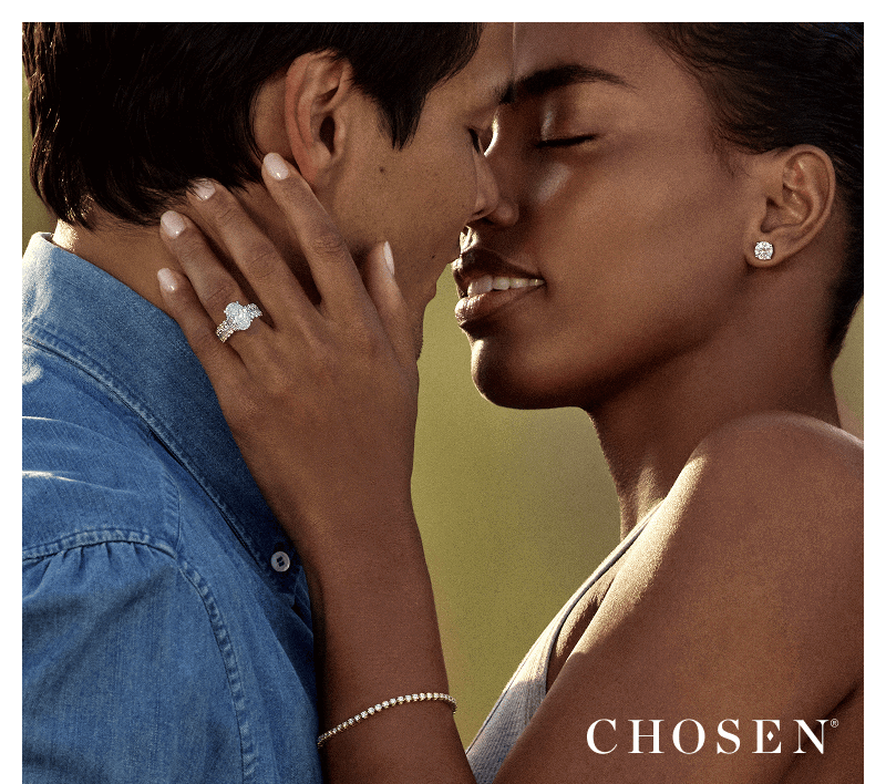 Close-up of woman wearing a diamond engagement ring holding her partner’s face. Chosen logo in corner.