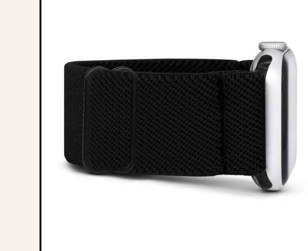A wrist with an Apple Watch and a black Braxley band, resting on a wooden surface.