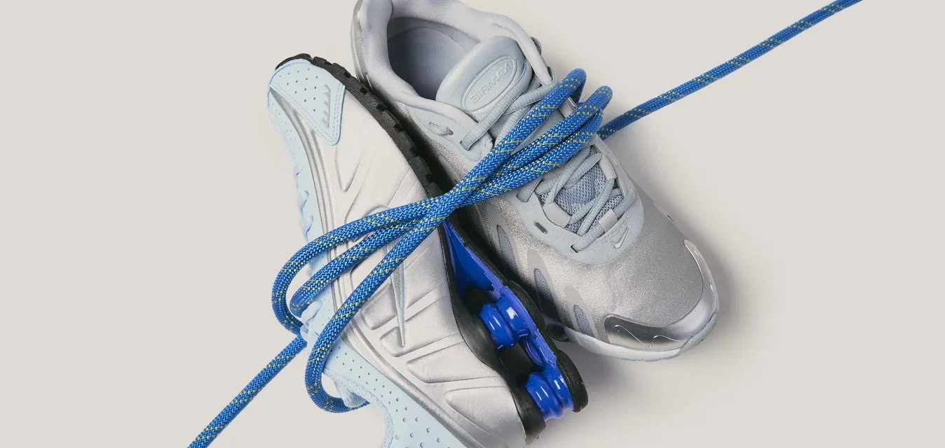 Een paar lichtgrijze en blauwe sportschoenen verstrengeld met een blauw touw op een lichte achtergrond.