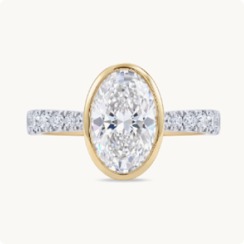 Oval Lab Grown Diamond 3 1/2ctw. Cathedral Engagement Ring in 14k Two Tone Gold: Oval-cut diamond ring with a yellow gold bezel setting and a pavé diamond band on a white gold shank.