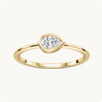Pear Lab Grown Diamond East West Bezel Petite Solitaire Engagement Ring in 10k Yellow Gold: Pear-shaped diamond ring with a yellow gold bezel setting and a thin, smooth gold band.