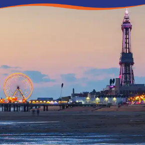 A coastal view featuring a illuminated tower and a Ferris wheel at dusk.