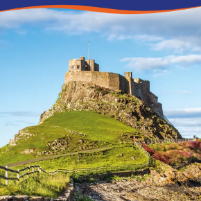 A historic castle perched on a grassy hill under a clear blue sky.