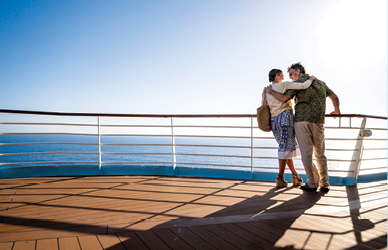 Couple taking a selfie on a cruise ship deck with sea views in the background.