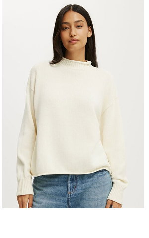Woman wearing cream knit sweater and blue jeans