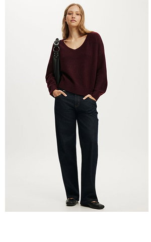 Woman wearing burgundy sweater and black jeans