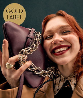 A smiling model carrying a burgundy leather handbag.