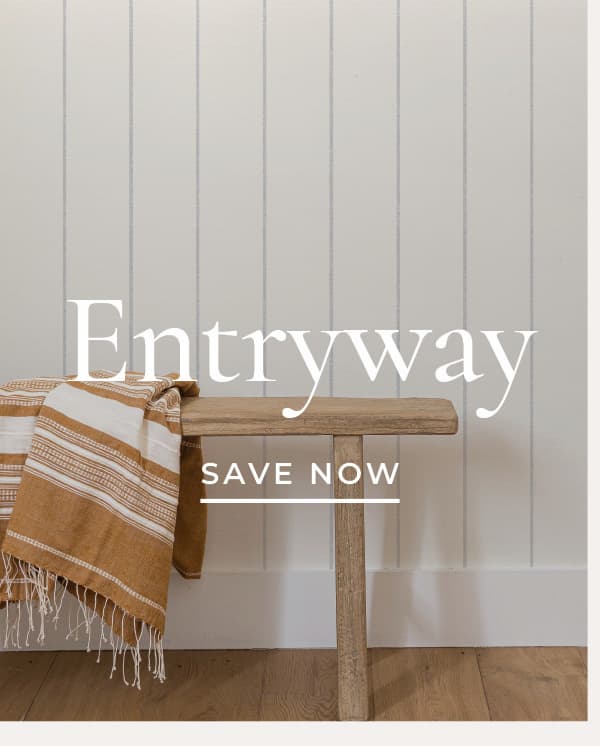 Image of Tempaper's Bursa Stripe wallpaper by Pure Salt installed in an entryway with a light colored wooden bench. Text overlay "Entryway Save Now"