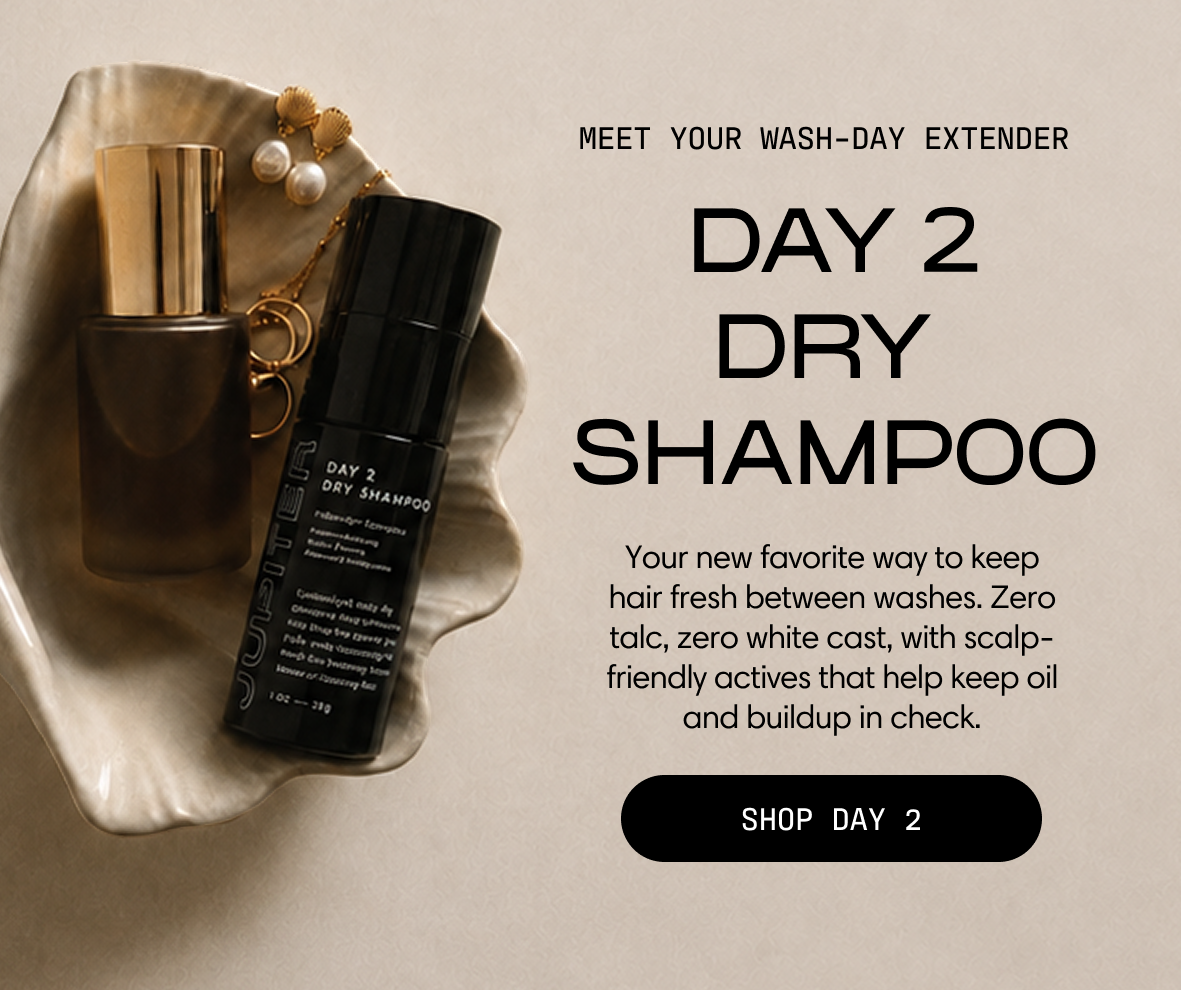 Meet your wash-day extender: Day 2 Dry Shampoo. Your new favorite way to keep hair fresh between washes. Zero talc, zero white cast, with scalp-friendly actives that help keep oil and buildup in check. The black bottle rests in a shell dish with a perfume bottle. Shop Day 2.