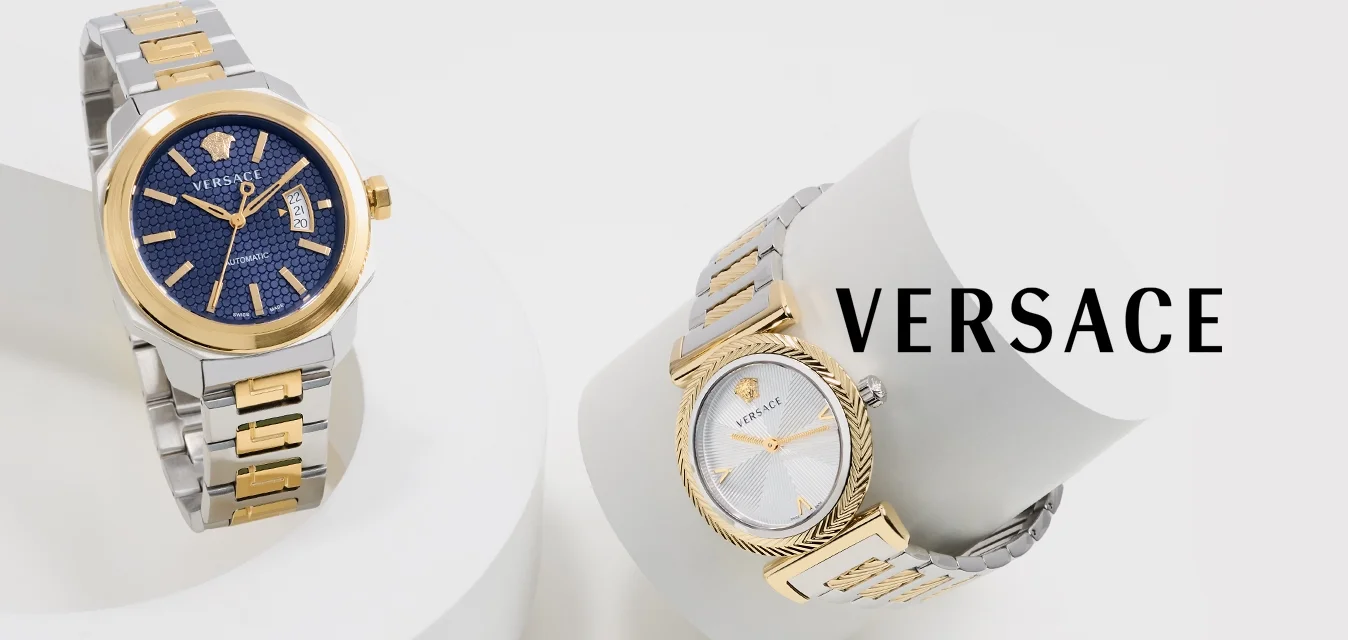 Twee Versace polshorloges met zilveren en gouden metalen bandjes op witte geometrische standaards, de een met een blauwe wijzerplaat, de ander met een witte wijzerplaat.