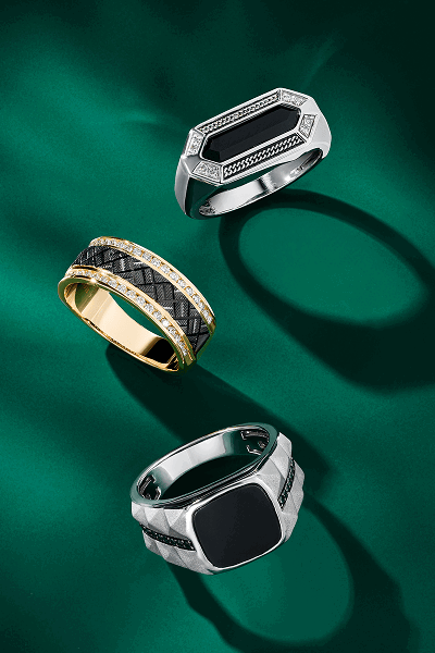 Three styles of men’s rings on green background.