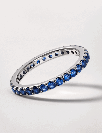 Sapphire eternity band in white gold with round blue gemstones.