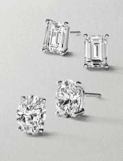 Emerald-cut and oval-cut diamond stud earrings in white gold.