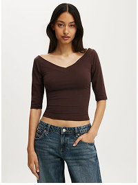 Woman wearing brown cropped v-neck top and jeans