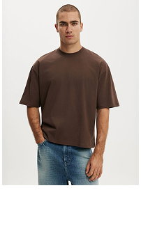 Man wearing brown oversized t-shirt and blue jeans