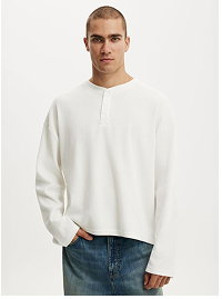 Man wearing cream long sleeve sweatshirt and jeans