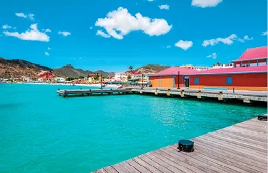 Colourful Caribbean waterfront with turquoise sea and a wooden pier.