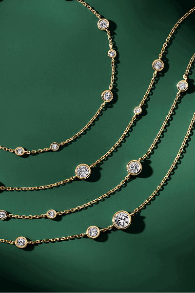 Women’s gold necklaces with diamonds on green background.