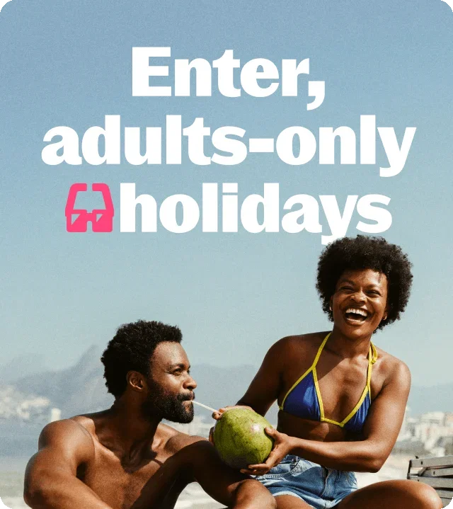 Blue-grey gradient background, white text 'Enter, adults-only holidays' with bright pink binoculars icon, smiling couple, man with afro and beard holding green coconut with straws, woman with voluminous afro in blue-yellow bikini, denim shorts, blurred coastal background, mountains and white buildings.