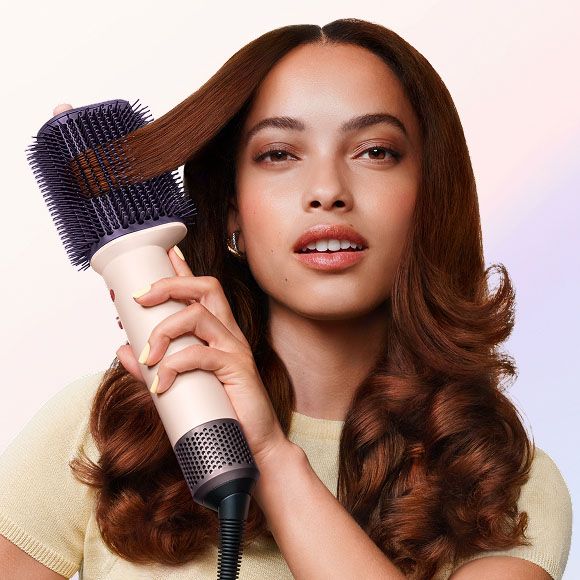 Model styling her hair with the Dyson Airsmooth styling brush.