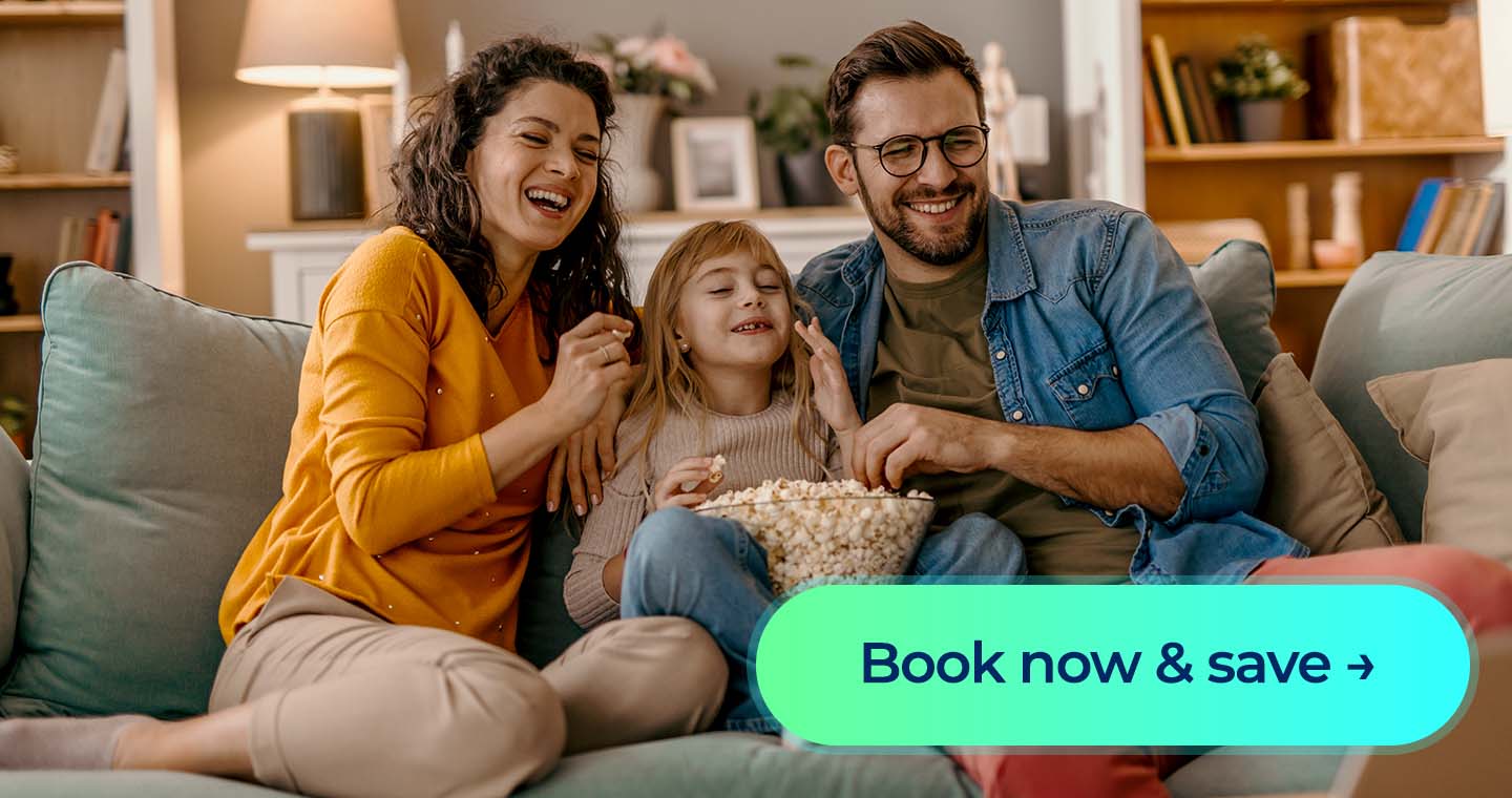A family laughing at a movie while sitting down on a couch