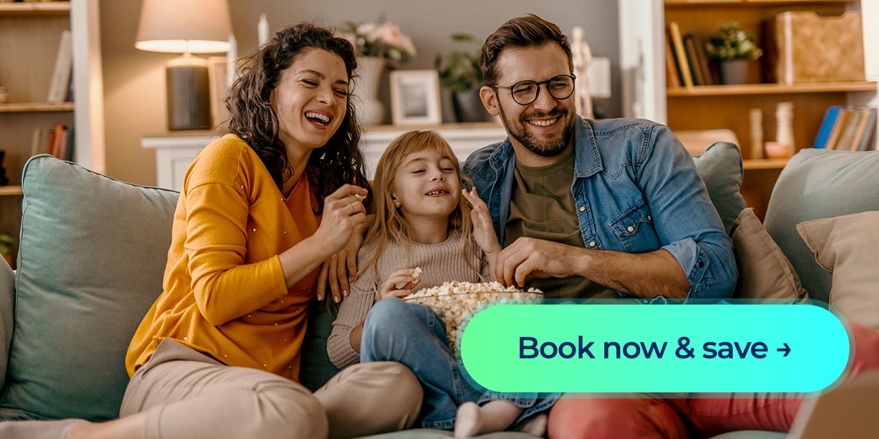 A family laughing at a movie while sitting down on a couch