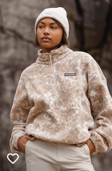 A woman wearing a tan fleece pullover and white beanie.