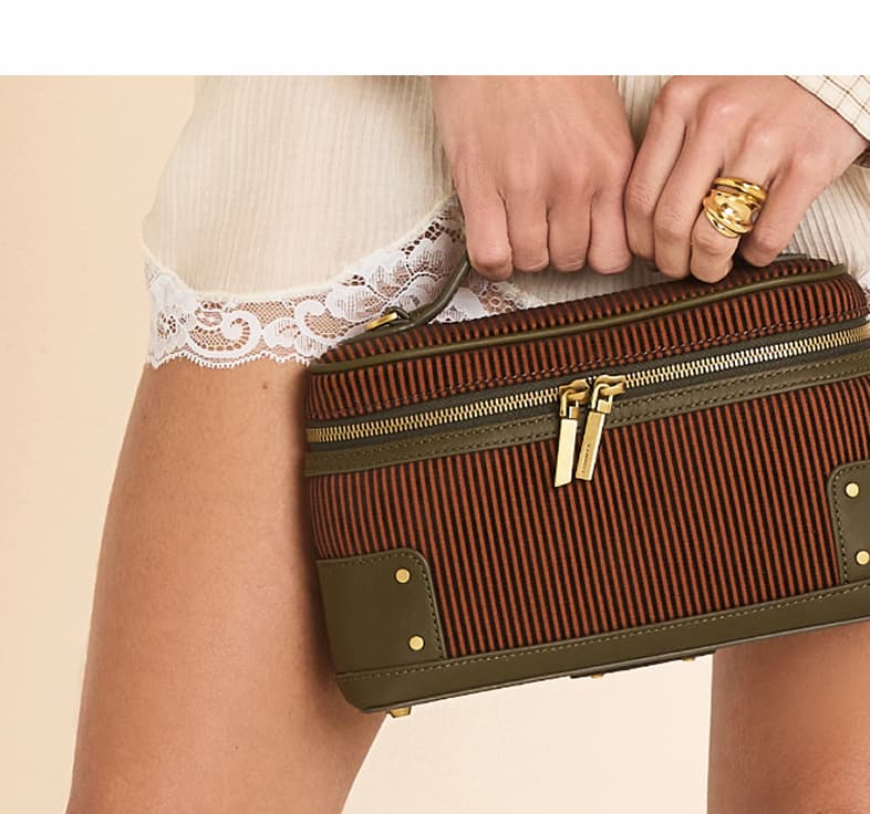 Close-up of a Tuscan Tandem bag featuring terracotta and espresso stripes, rich green leather trim, gold hardware, and double-zip closure.