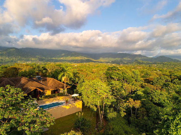 Hillside villa with scenic pool overlooking a verdant rainforest and distant mountains.
