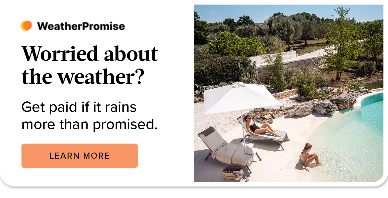 Loungers and an umbrella beside a resort-style pool surrounded by trees.