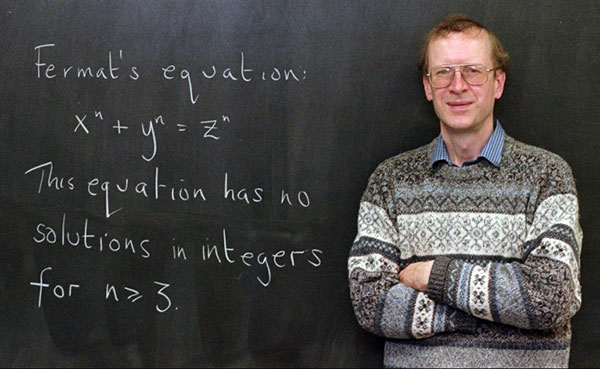 Mathematician Andrew Wiles poses next to a blackboard that has Fermat's Last Theorem written on it in chalk.