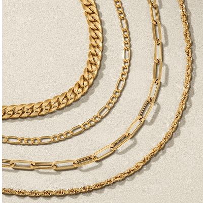 Four various gold chain necklaces on textured background.