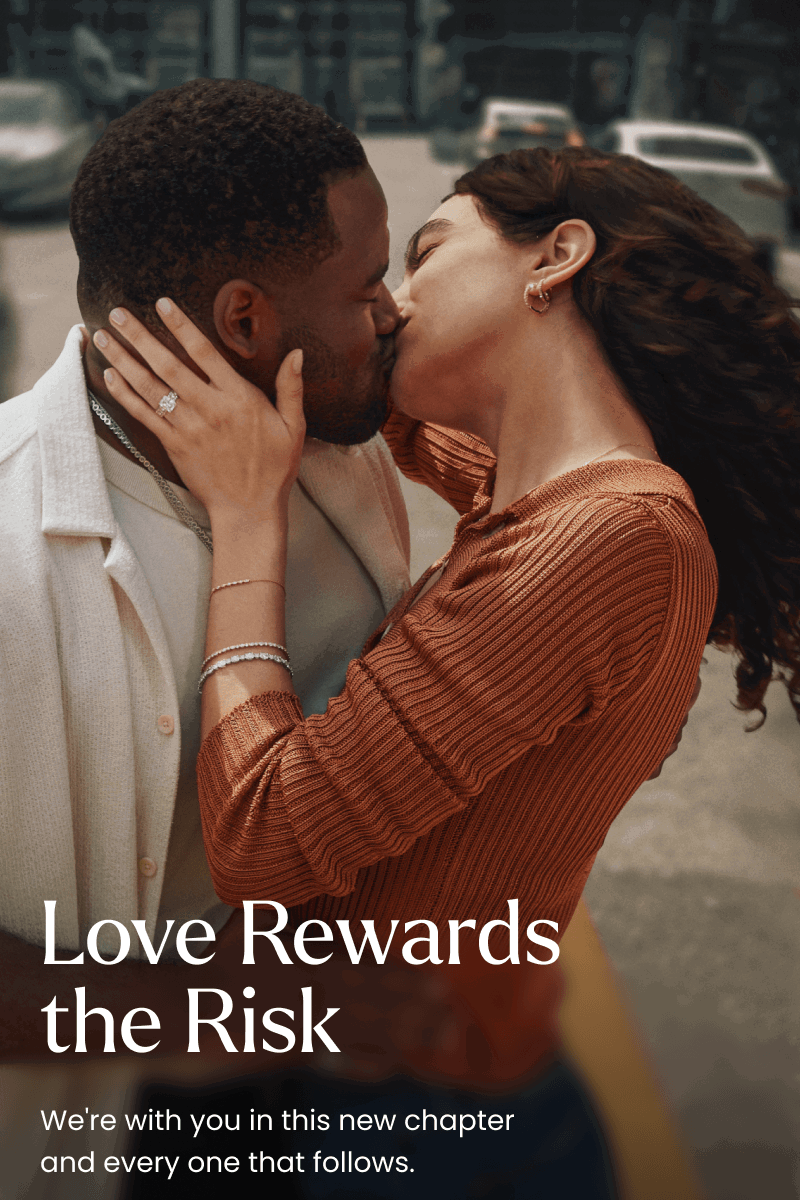 Couple kissing. Woman is wearing layered bracelets, earrings and a diamond ring. Love rewards the risk.