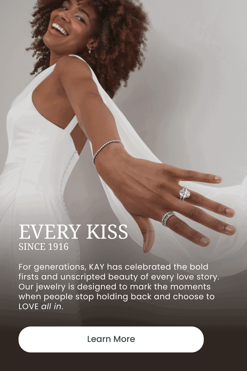 Bride wearing diamond tennis bracelet and rings. Every kiss since 1916. Choose to love all in. Click learn more.